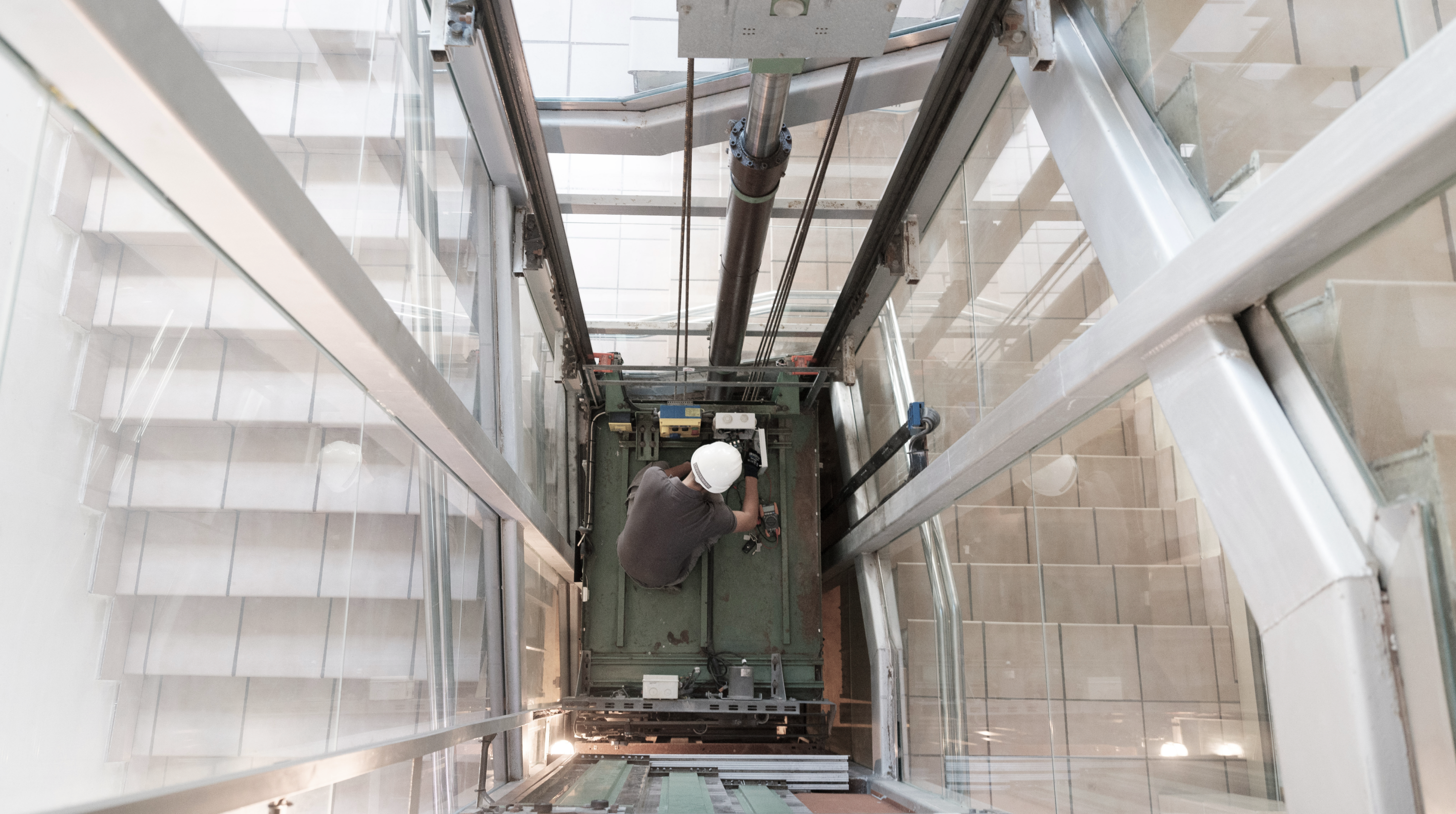 Técnico de ascensores Eguzkimendi haciendo el mantenimiento de un ascensor integrado en un edificio con escaleras. 